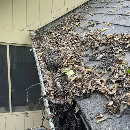 A gutter packed with leaves and debris before a Two Men and a Gutter cleaning